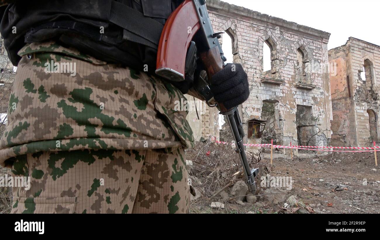 AGDAM, AZERBAIJAN - DECEMBER 14: Azerbaijani soldier looking at a ruined building in the town of Agdam which was destroyed by Armenian forces during the First Nagorno-Karabakh War on December 14, 2020 in Agdam, Azerbaijan. The town and its surrounding district were returned to Azerbaijani control as part of an agreement that ended the 2020 Nagorno-Karabakh War. Stock Photo