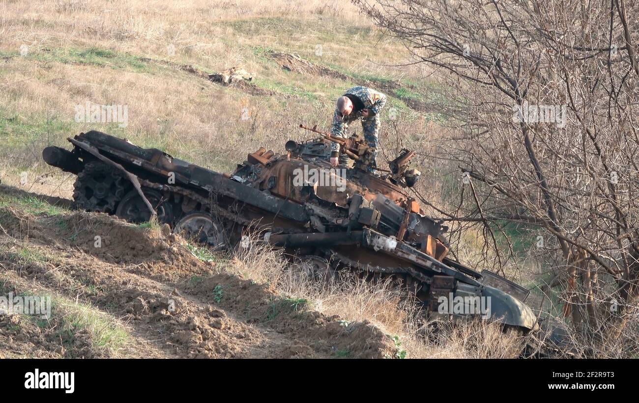 JABRAYIL, AZERBAIJAN - DECEMBER 15: A member of the Russian peacekeeping troops force examines a destroyed T-72 Armenian tank for remains of Armenian fighters killed in the conflict over the disputed region of Nagorno-Karabakh on December 15 2020 in the Jabrayil Rayon of Azerbaijan. Heavy clashes erupted over Nagorno-Karabakh in late September during which more than 5,600 people, including civilians, were killed. The sides agreed to a Russia-brokered cease-fire deal that took effect on November 10 Stock Photo