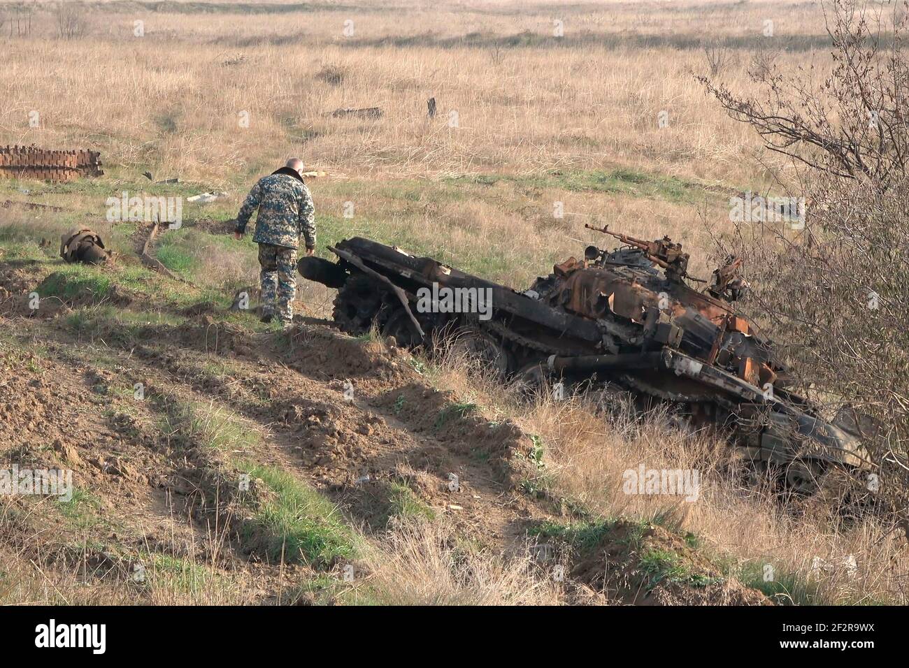 JABRAYIL, AZERBAIJAN - DECEMBER 15: A member of the Russian peacekeeping troops force examines a destroyed Armenian T-72 tank for remains of Armenian fighters killed in the conflict over the disputed region of Nagorno-Karabakh on December 15 2020 in the Jabrayil Rayon of Azerbaijan. Heavy clashes erupted over Nagorno-Karabakh in late September during which more than 5,600 people, including civilians, were killed. The sides agreed to a Russia-brokered cease-fire deal that took effect on November 10 Stock Photo