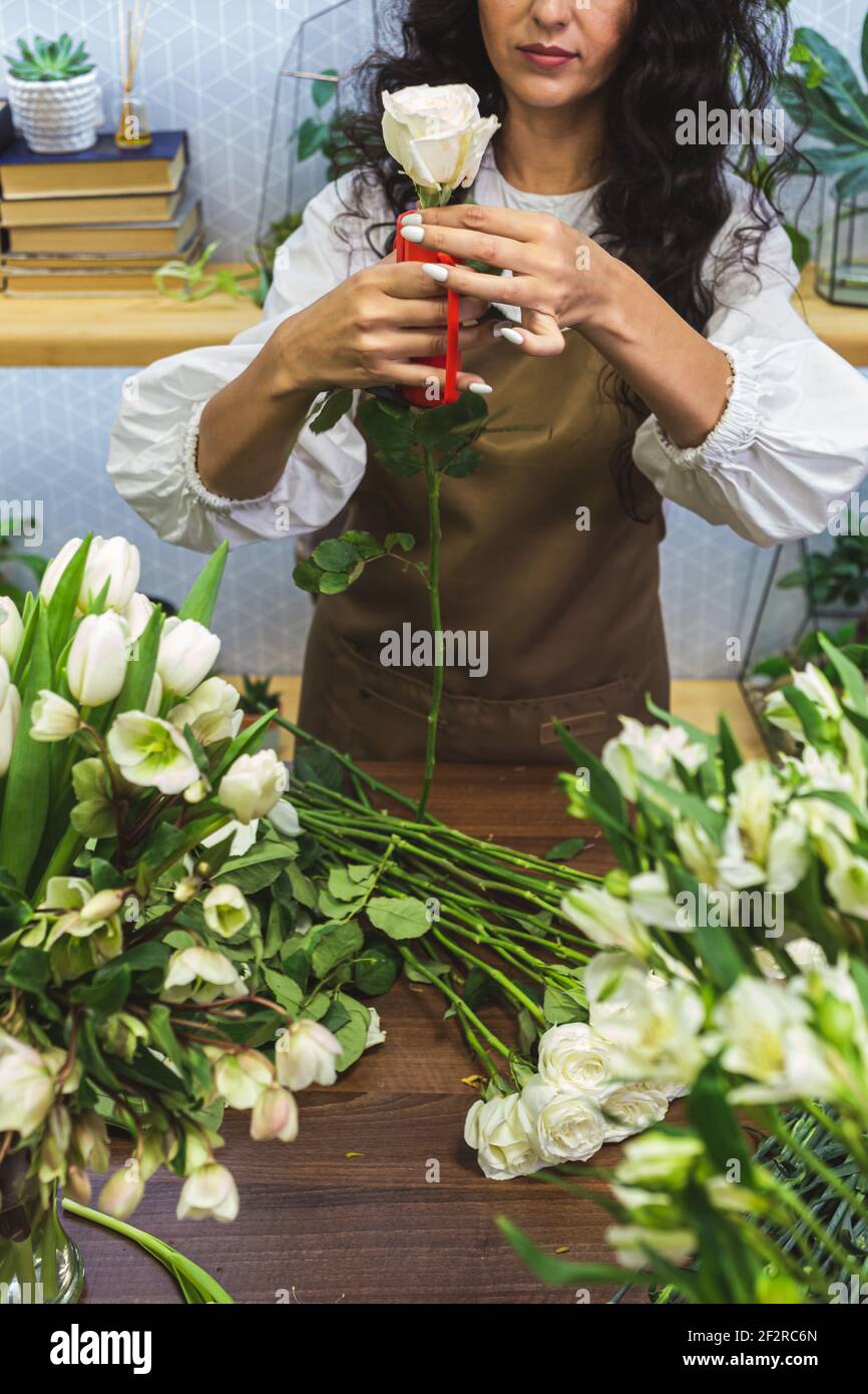 Attractive young woman florist is working in a flower shop Stock Photo ...