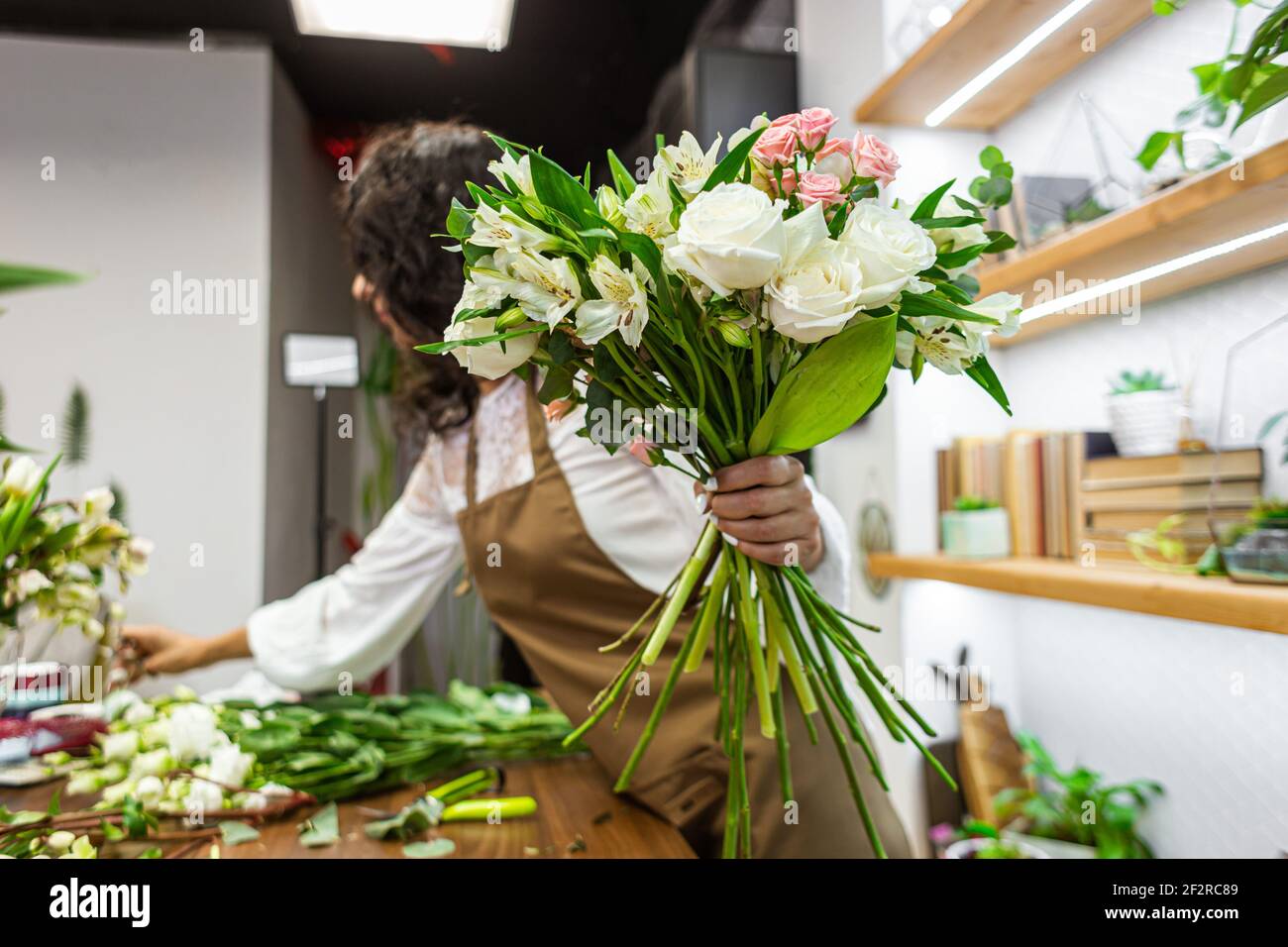 Attractive young woman florist is working in a flower shop Stock Photo ...