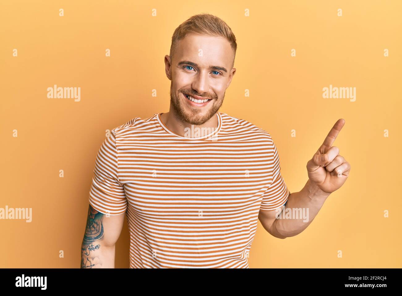 Young caucasian man wearing casual striped t-shirt smiling with an idea ...