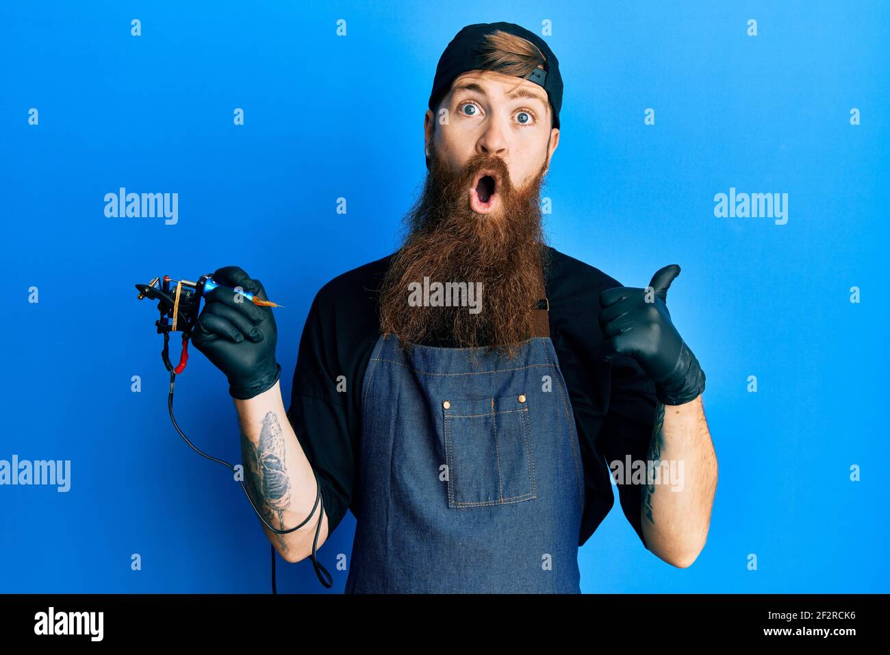 Redhead man with long beard tattoo artist wearing professional uniform and gloves surprised pointing with hand finger to the side, open mouth amazed e Stock Photo - Alamy Redhead man with long beard tattoo artist wearing professional uniform and gloves surprised pointing with hand finger to the side, open mouth amazed e Stock Photo - Alamy