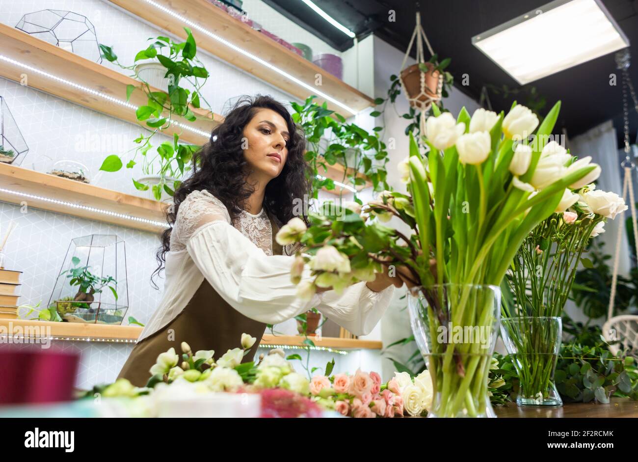 Attractive young woman florist is working in a flower shop Stock Photo ...