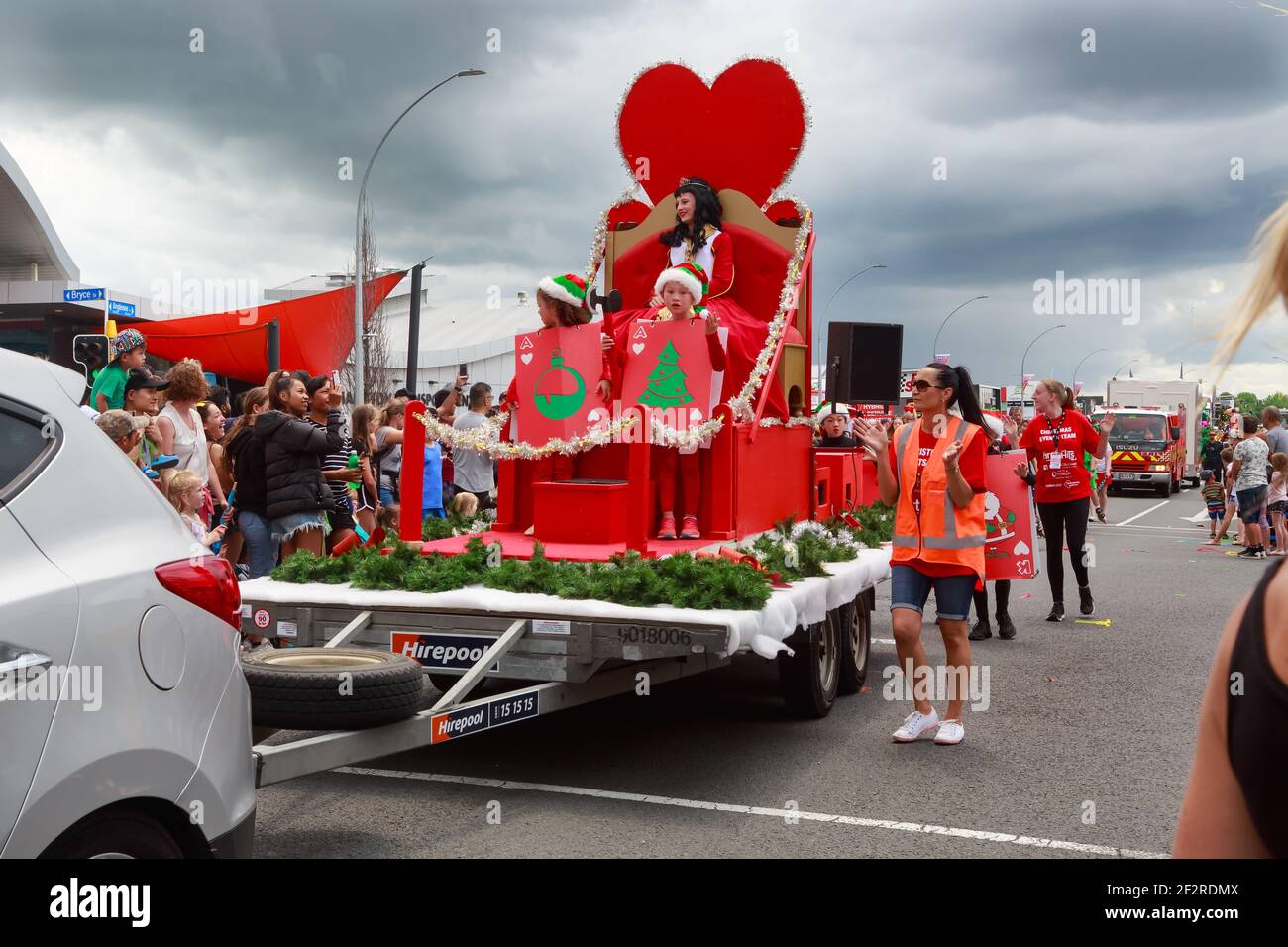 A woman dressed as the Queen of Hearts at a Christmas parade, with children dressed as playing cards, all riding on a parade float Stock Photo