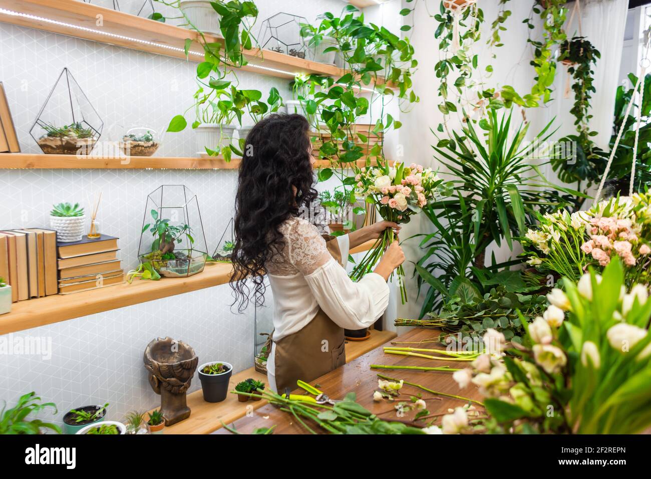 Attractive young woman florist is working in a flower shop Stock Photo ...