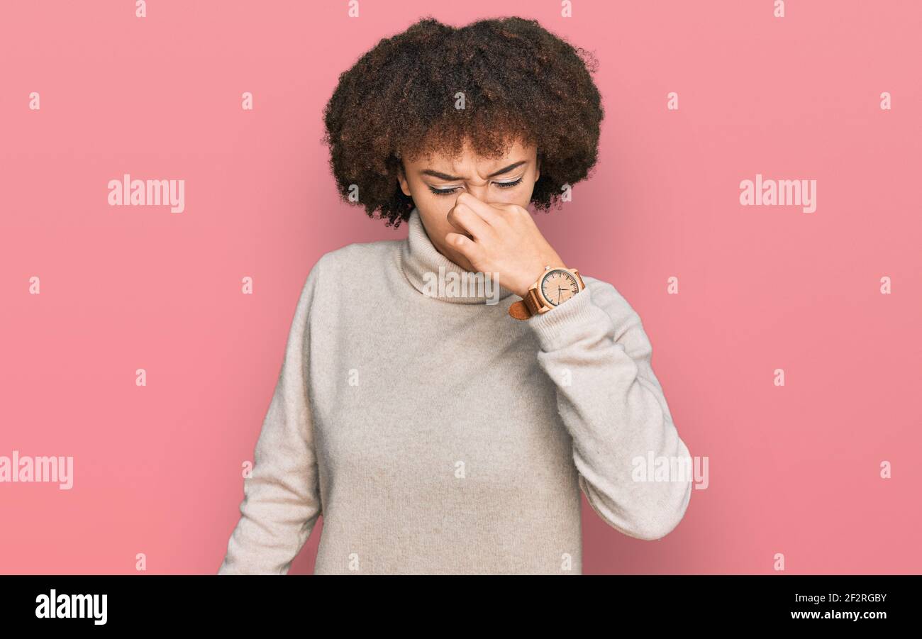 Young hispanic girl wearing wool winter sweater smelling something
