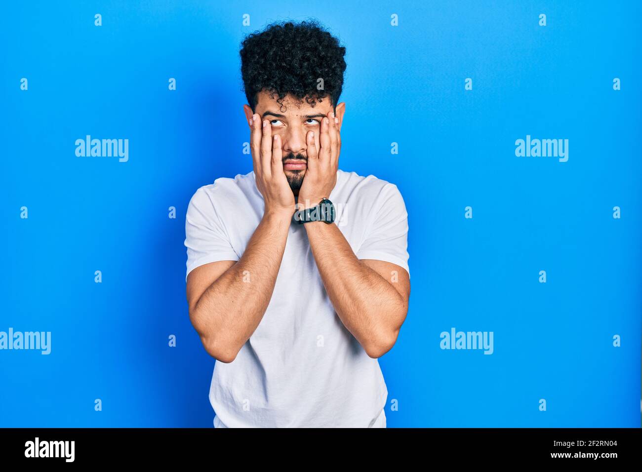 Young arab man with beard wearing casual white t shirt tired hands ...