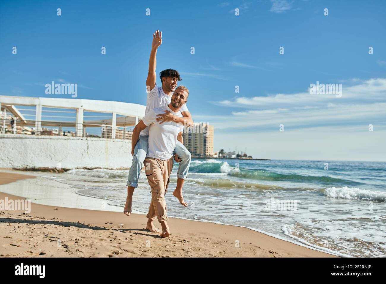 Lovely gay couple on piggyback ride at the beach Stock Photo - Alamy