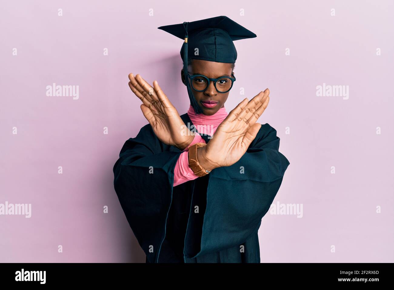 Young african american girl wearing graduation cap and ceremony robe rejection expression crossing arms doing negative sign, angry face Stock Photo