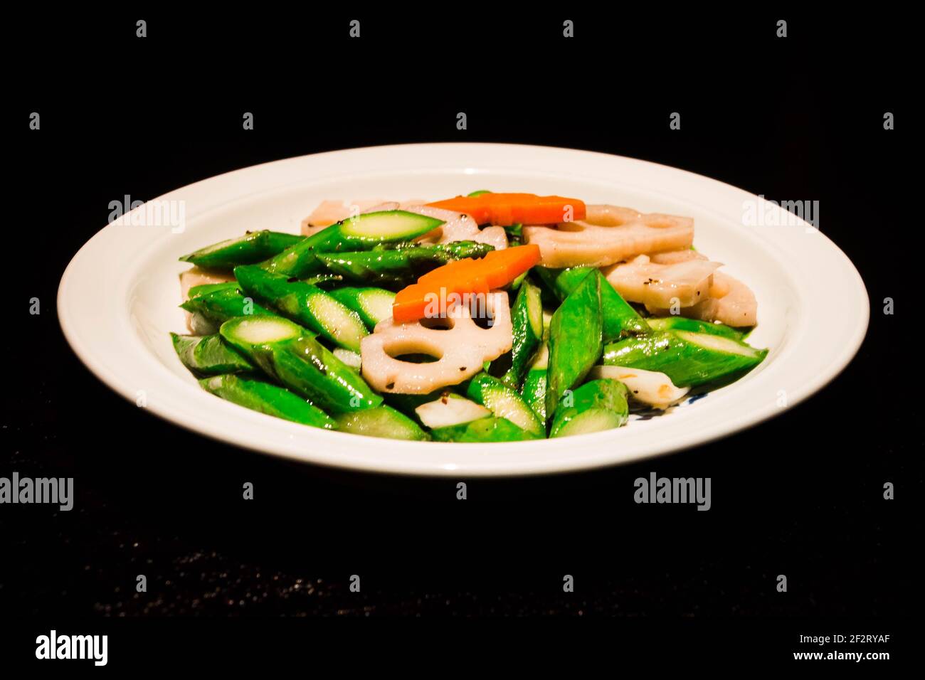 asparagus stir fried with lotus root and carrot serrved in a white plate Stock Photo