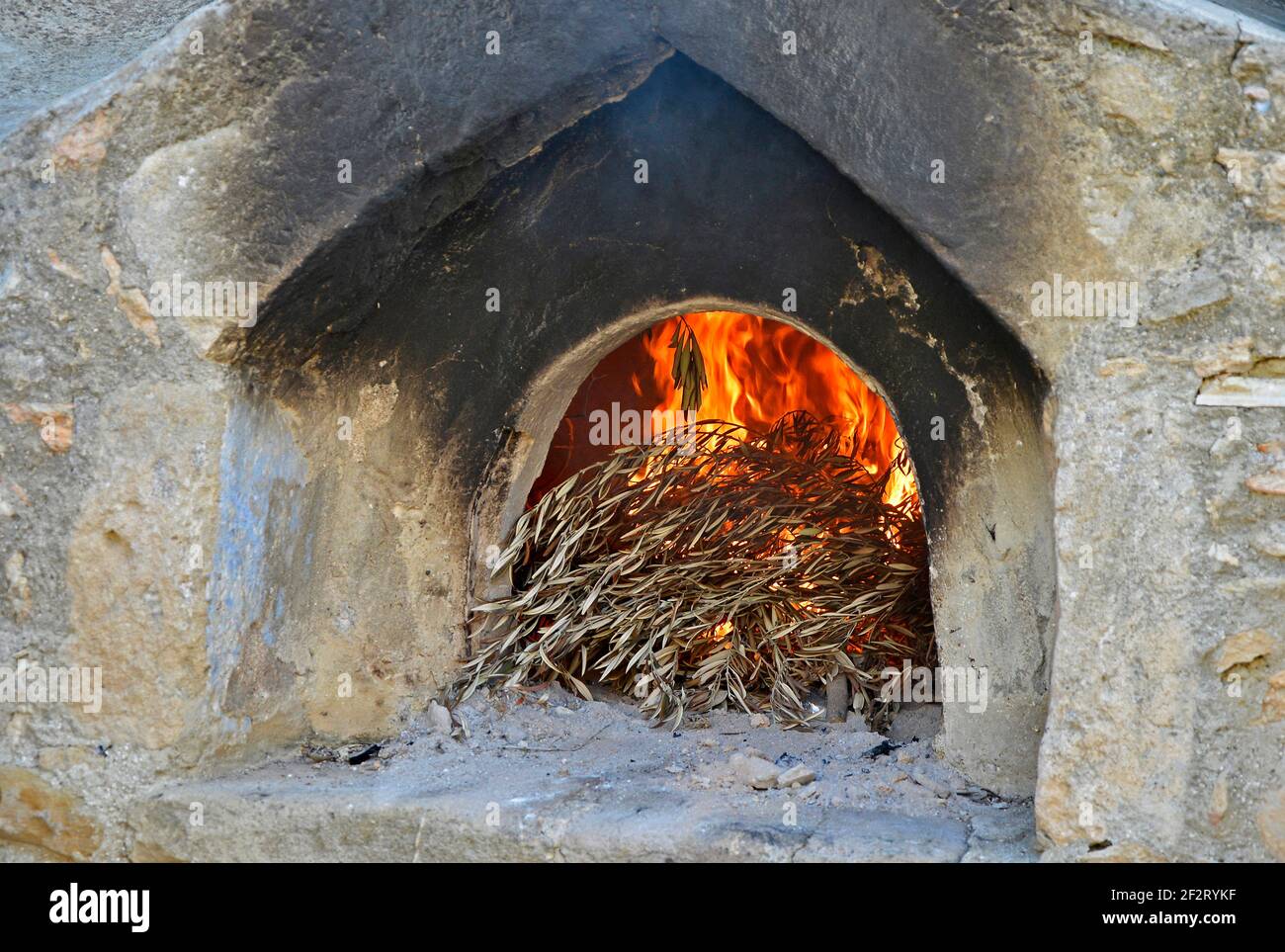 A traditional old Cyptiot stone outdoor wood fired oven with burning olive branches Stock Photo