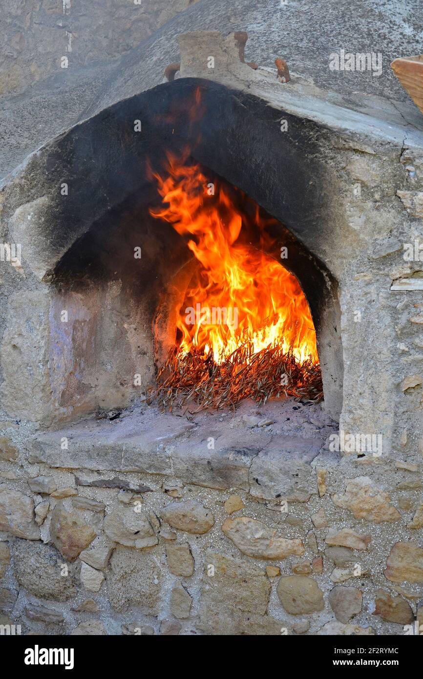 A traditional old stone outdoor wood fired oven with burning olive branches Stock Photo