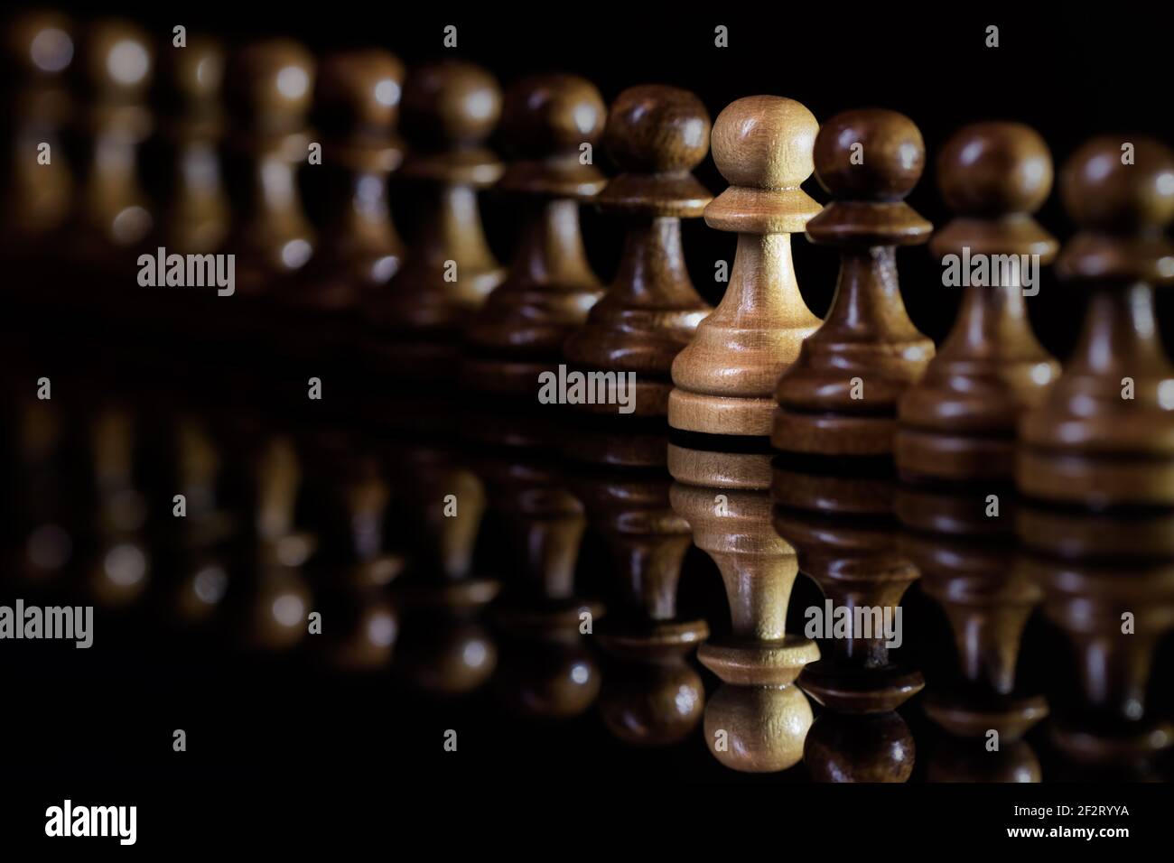 One different pawn chess piece in a row. Unique identity and individuality concept. Black background Stock Photo