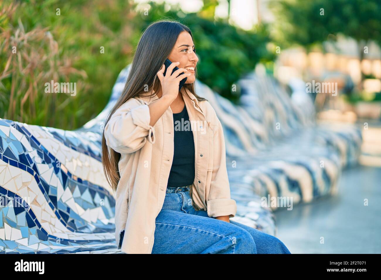 Young hispanic girl smiling happy talking on the smartphone at the park ...