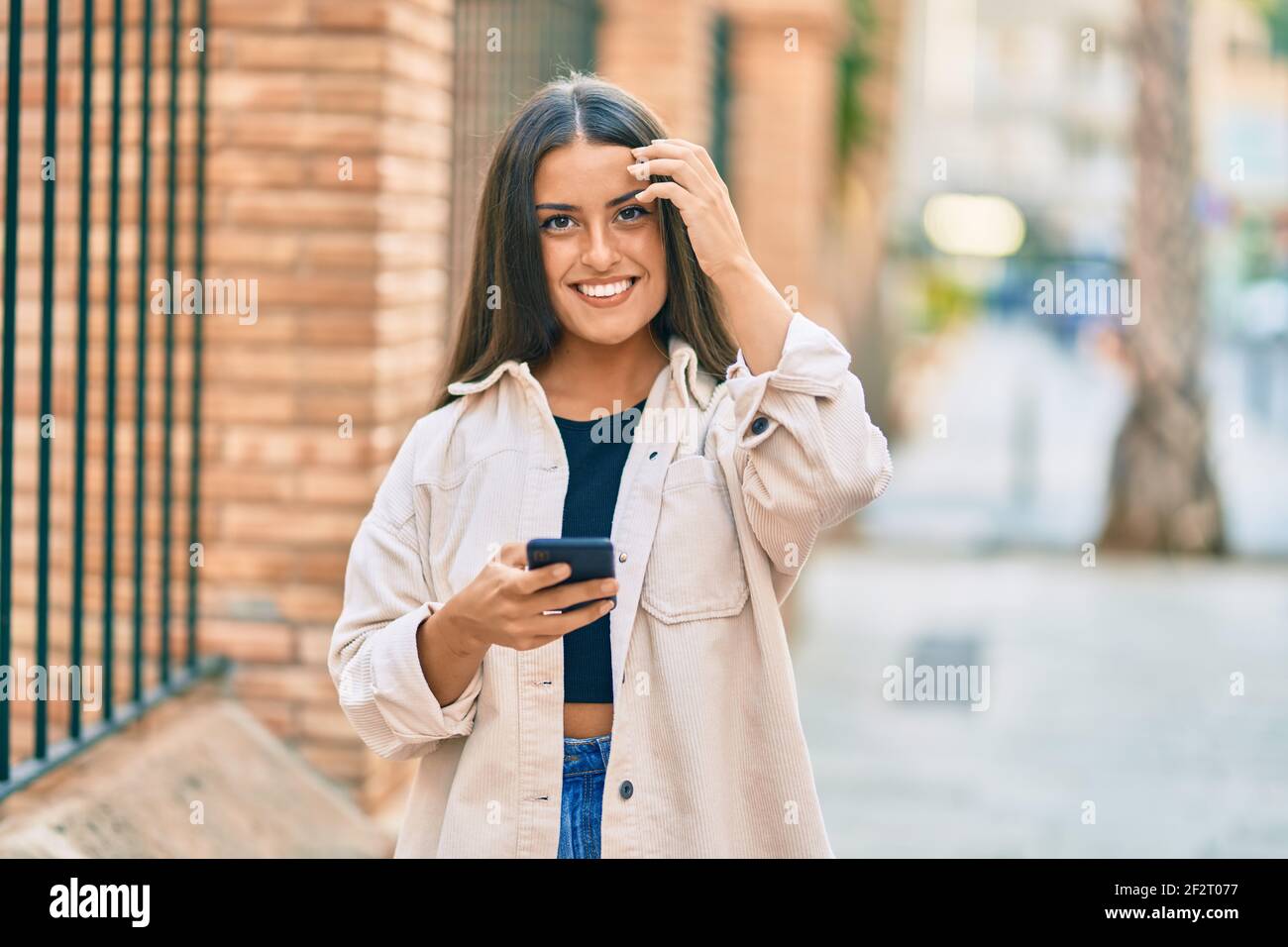 Young hispanic girl smiling happy using smartphone at the city Stock ...