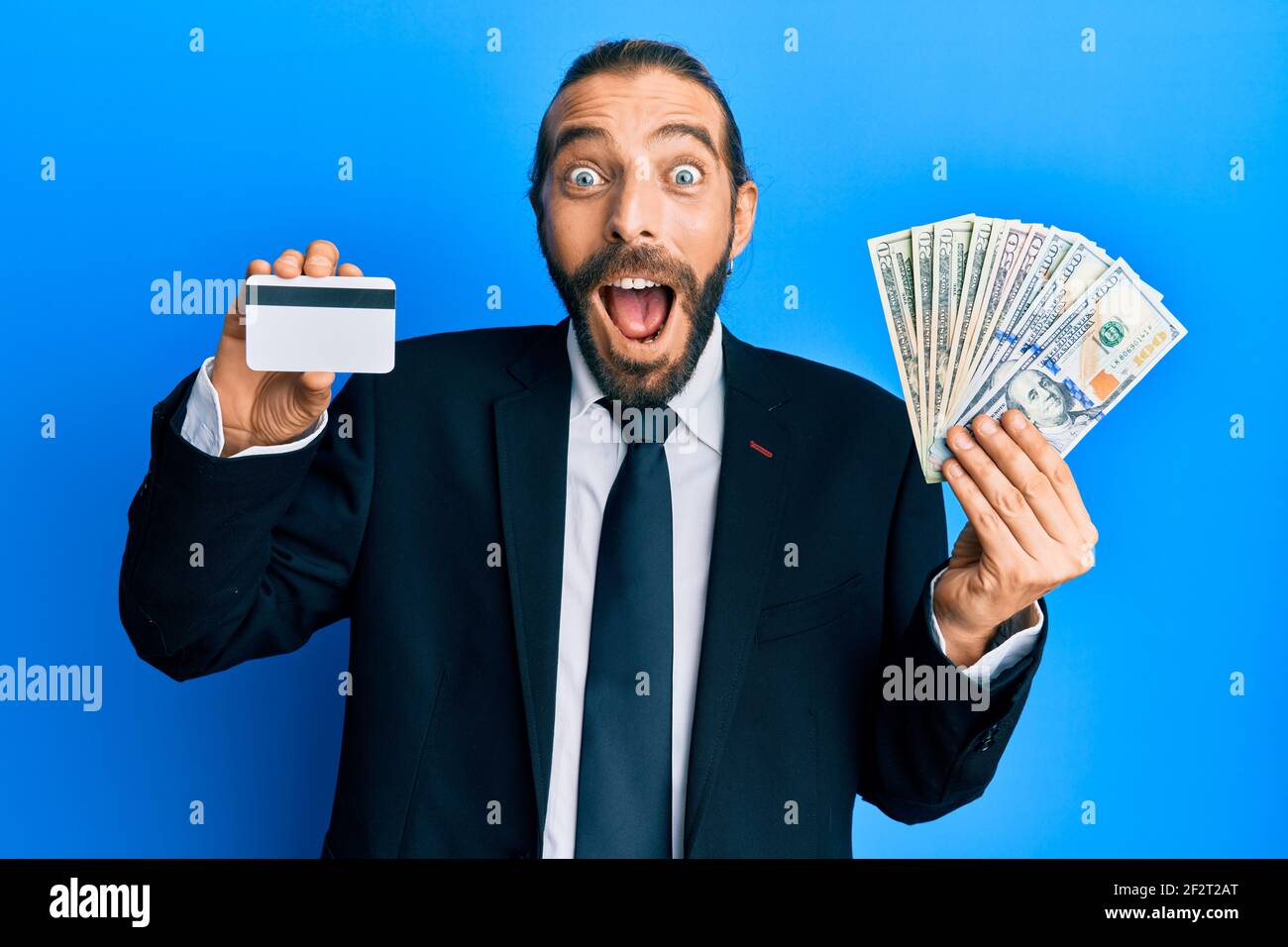 Attractive business man with long hair and beard holding credit card ...