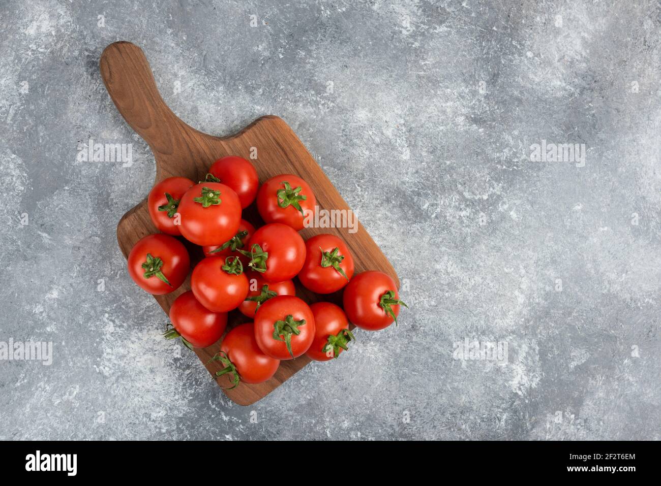 Bunch of red fresh tomatoes on wooden cutting board Stock Photo