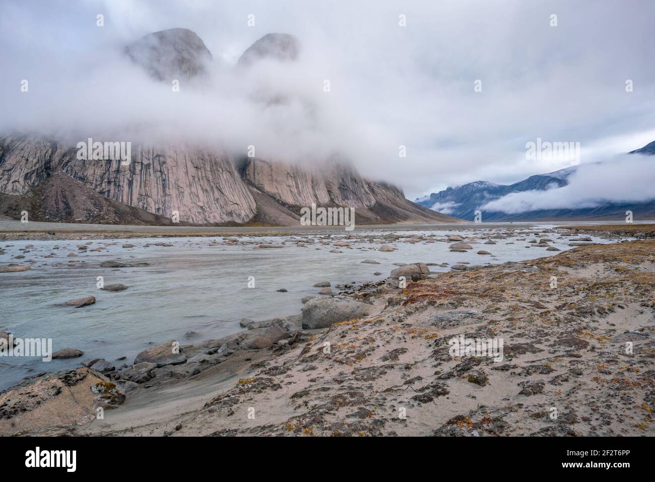 Majestic granite rocks by the surface. Wild arctic landscape of Akshayuk Pass, Baffin Island, Canada on a cloudy, rainy day of arctic summer. Stock Photo