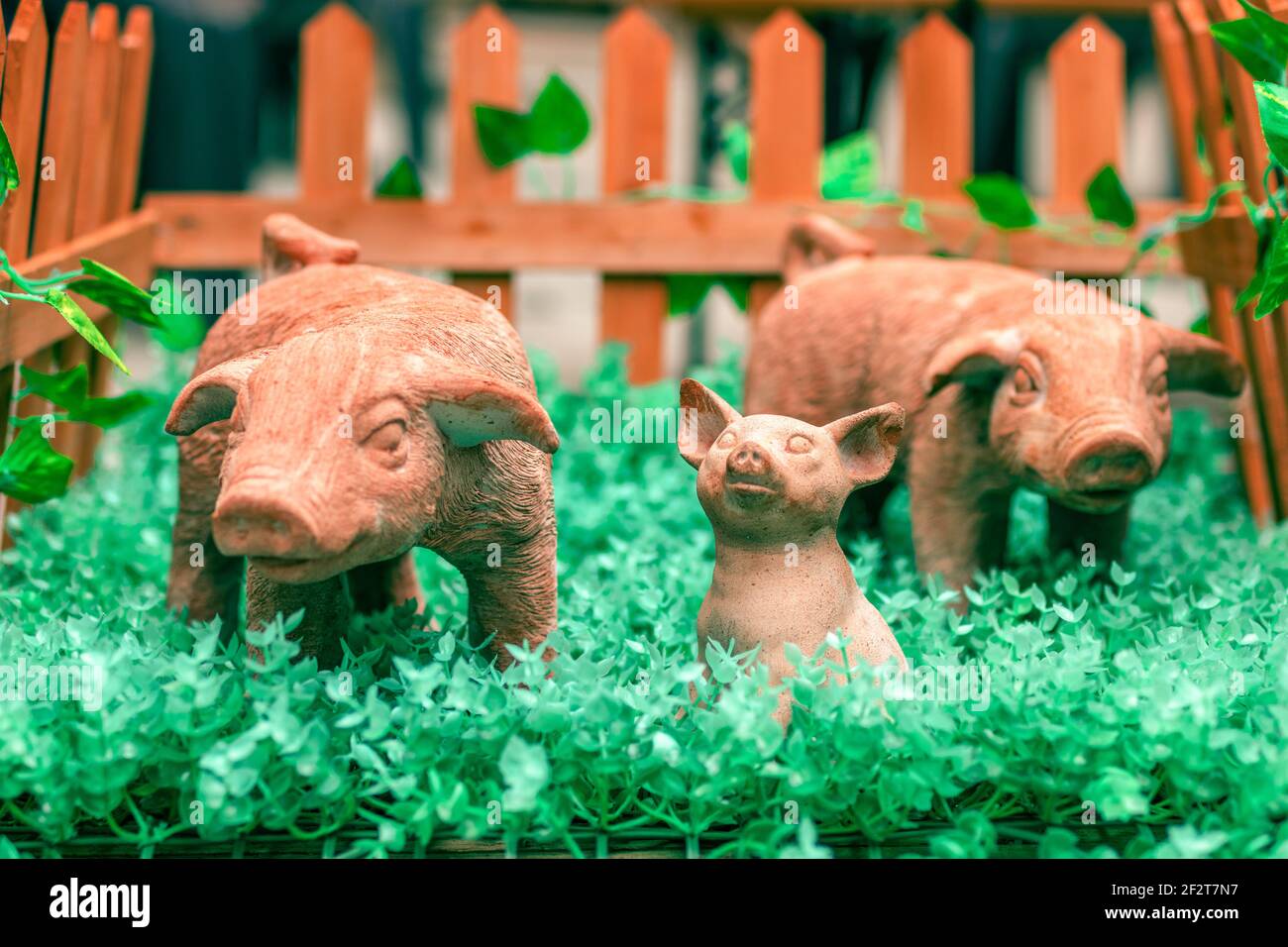 Symbol of the new year 2019. Newborn ceramic toy pig surrounded by his mom and dad in a tay animal pen. Chinese horoscope year of the pig. 2019 new ye Stock Photo