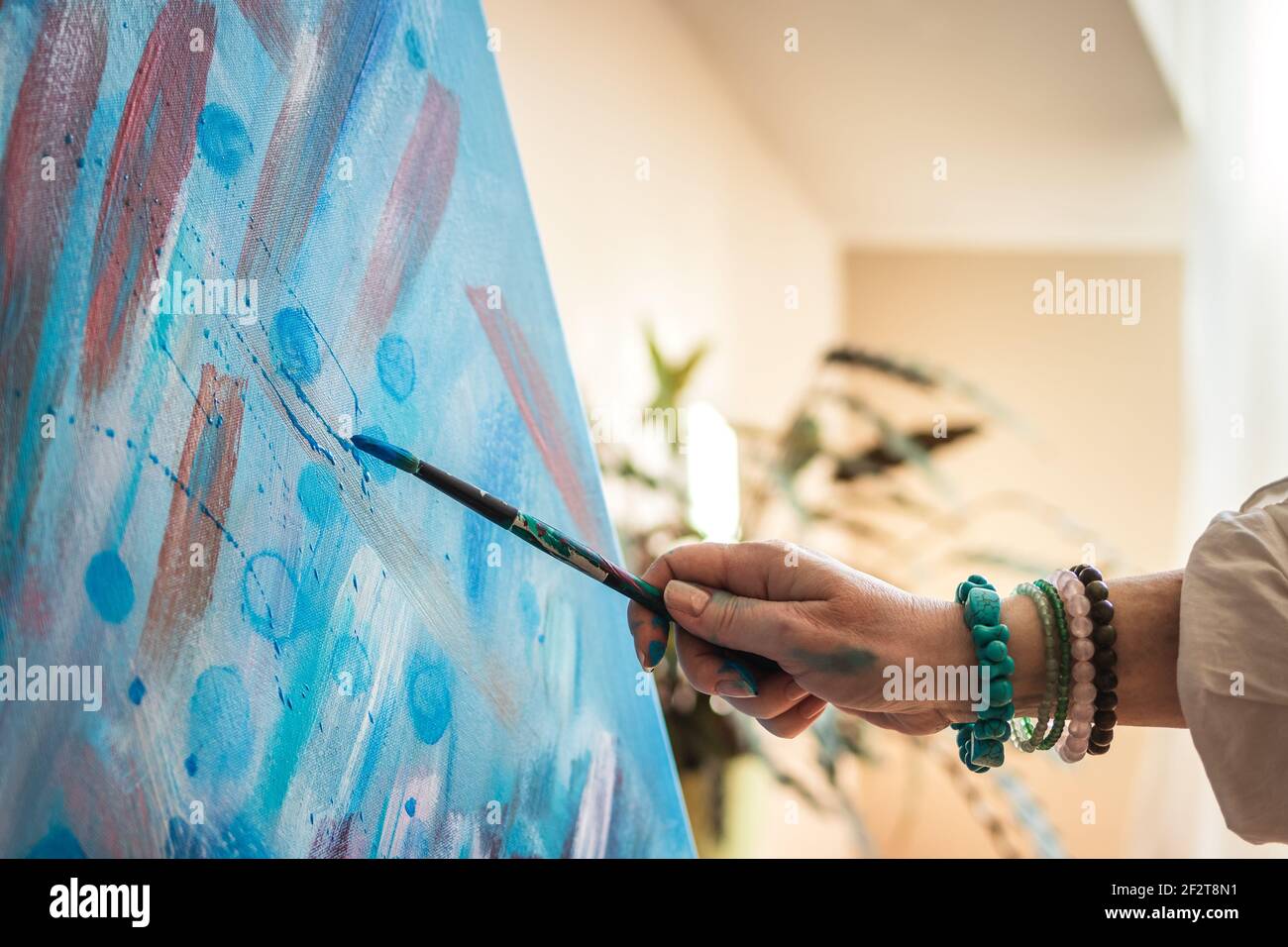 Painting on canvas by using dripping technique with paintbrush