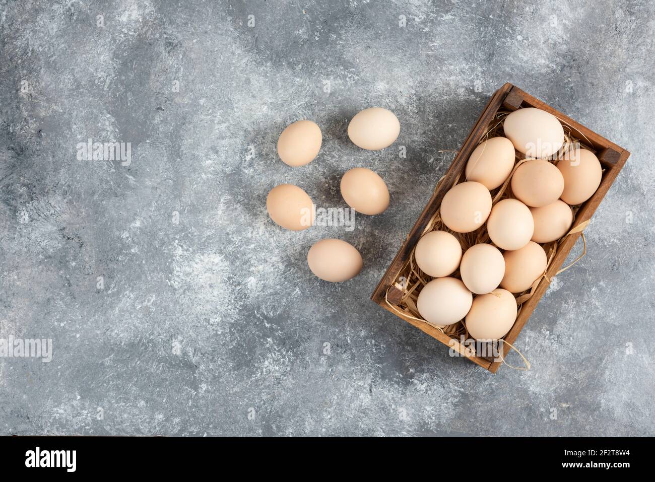 Wooden box of organic raw eggs on marble surface Stock Photo