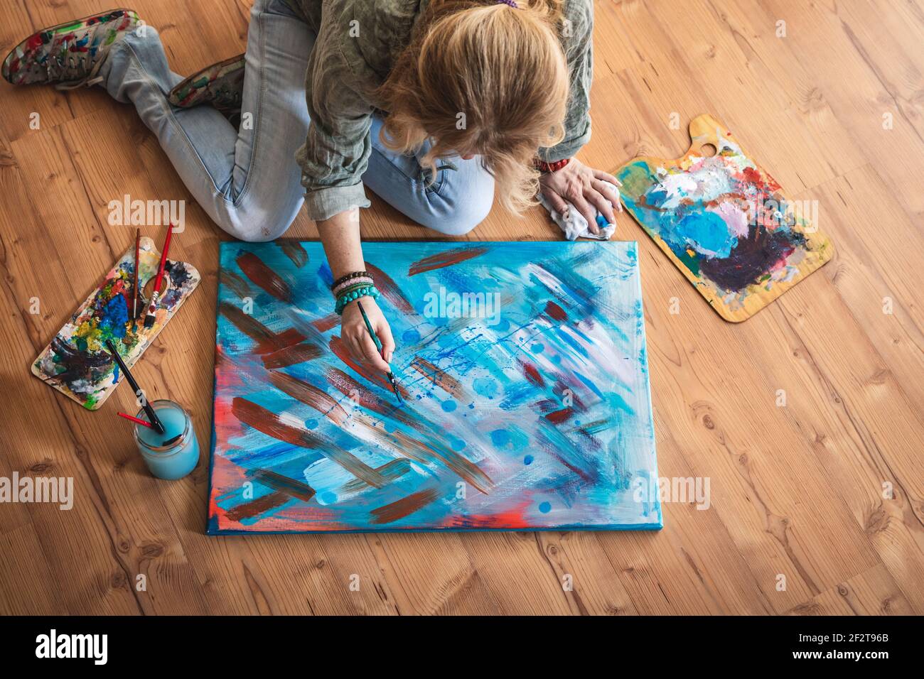 Oil painting. Artist sitting on floor and working on her abstract ...