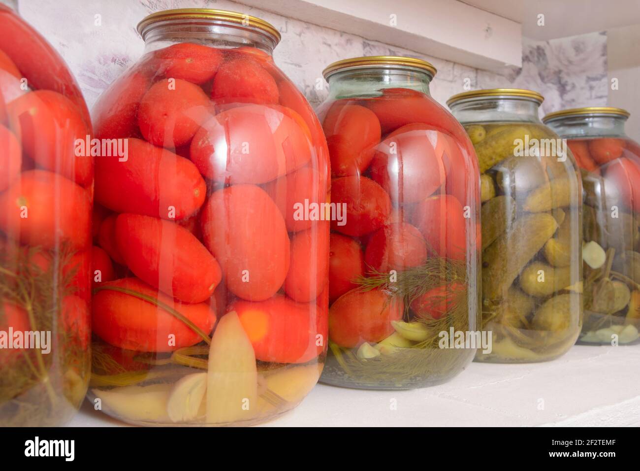 Pickled vegetables in large jars on shelf. Harvesting tomatoes and cucumbers for winter. Close-up, selective focus. Stock Photo