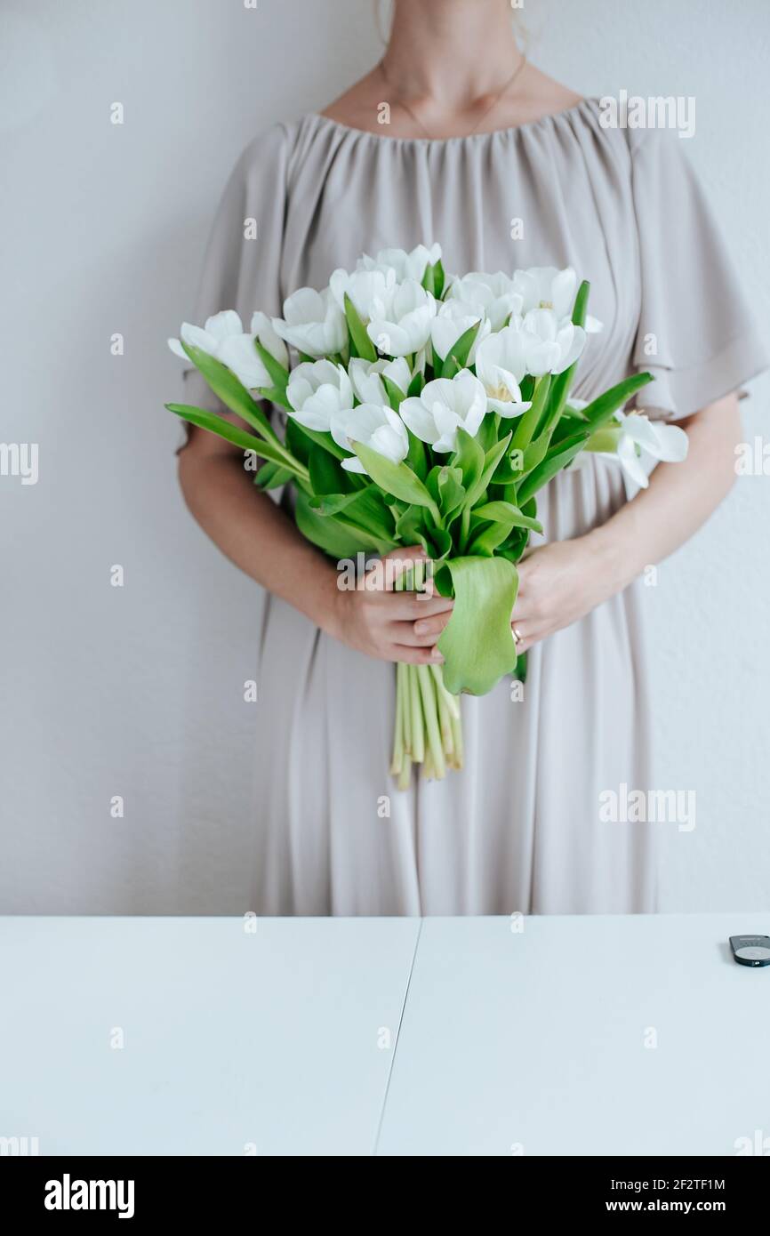 Beautiful tulips on a wooden cutting board, nordic mood or nordic living. The woman is holding flowers to bring on more nordic food. Stock Photo