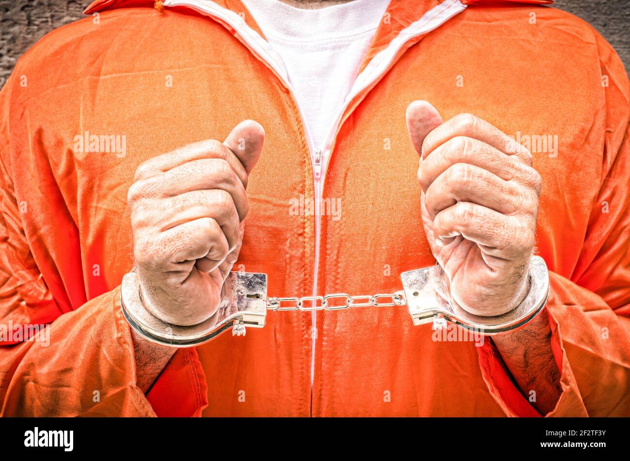 Handcuffed hands of prisoner - Guantanamo prison orange clothes Stock Photo