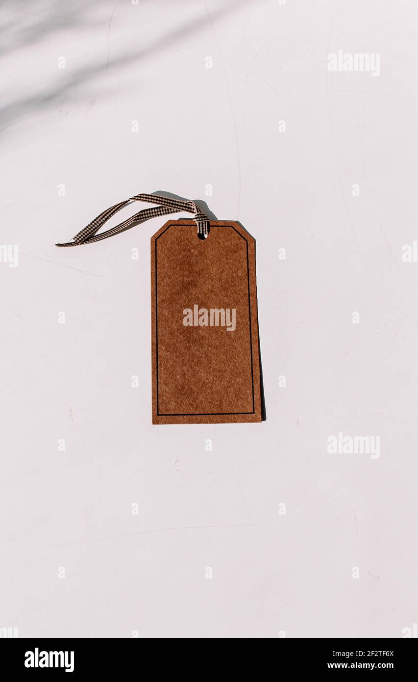 Brown tag with a glass on a white table with shades, add a text on a tag or your own design element Stock Photo