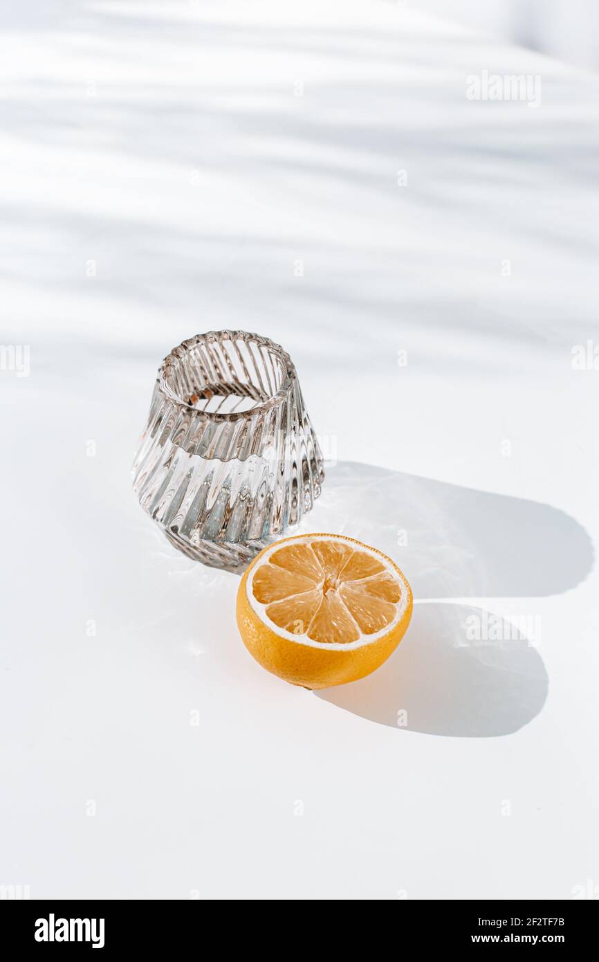 White Crystal class with lemon on a white or yellow surface, for healthy and holistic living Stock Photo