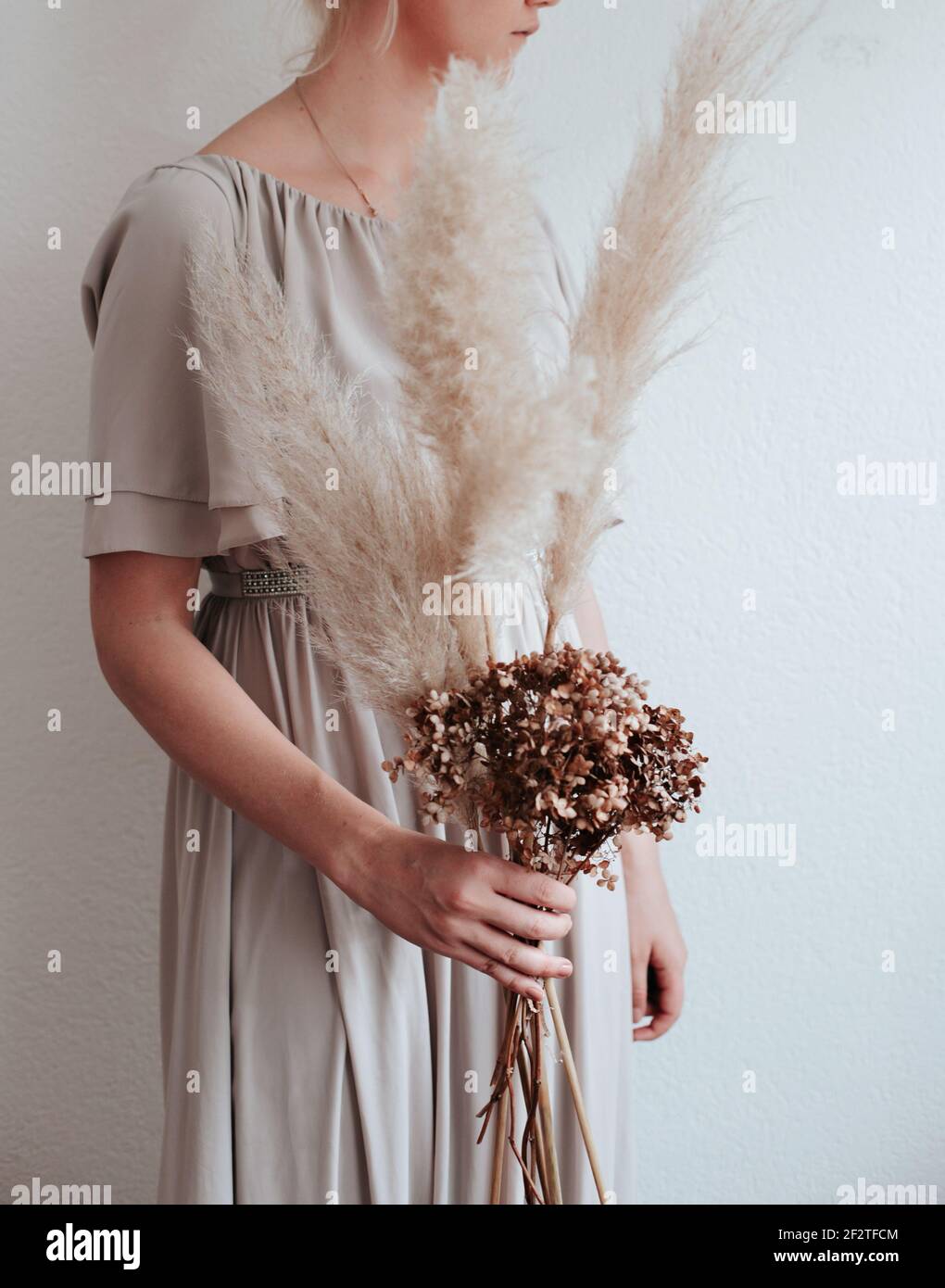 Woman holding pampas grass and brown flowers for a nordic living, feeling, beige, grey aesthetic Stock Photo