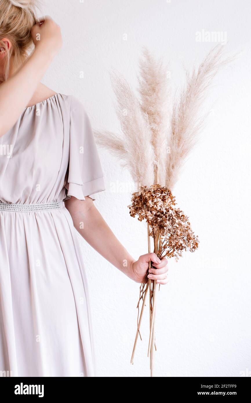 Woman holding pampas grass and brown flowers for a nordic living, feeling, beige, grey aesthetic Stock Photo