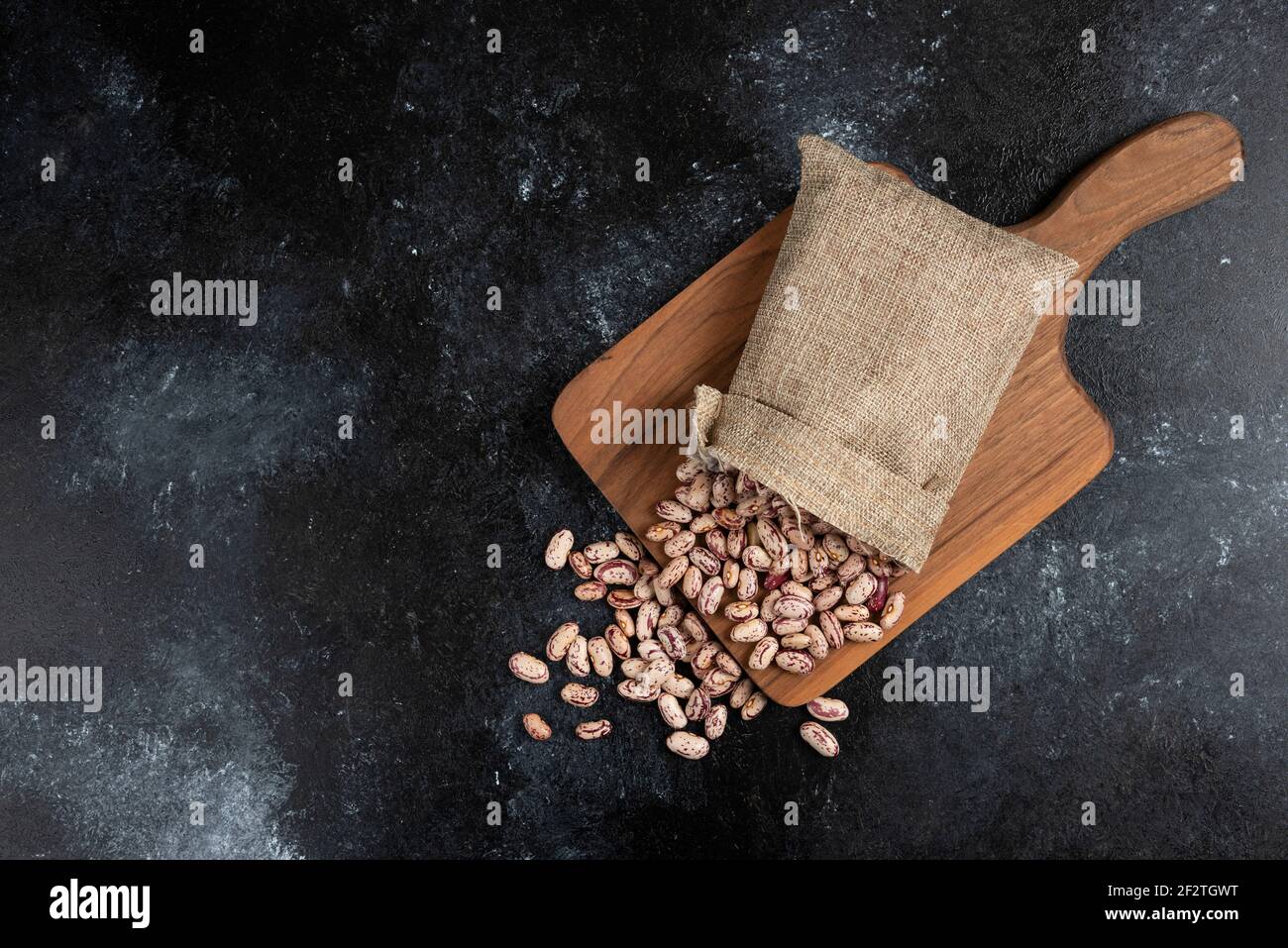Sackcloth of dried raw beans placed on wooden board Stock Photo