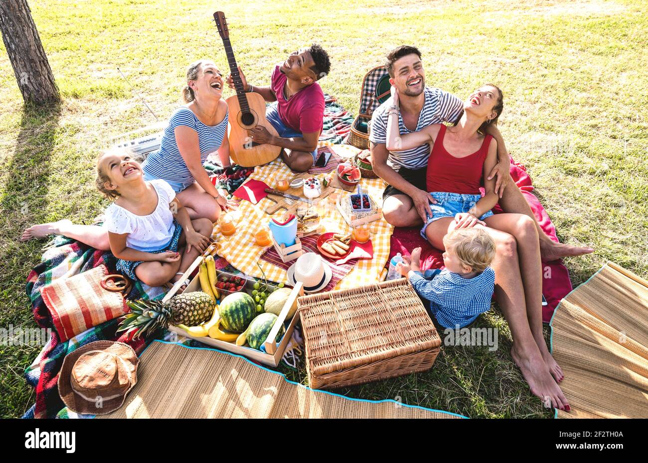 High angle top view of happy family having fun with kids at pic nic barbecue party - Multiracial love concept with mixed race people playing together Stock Photo