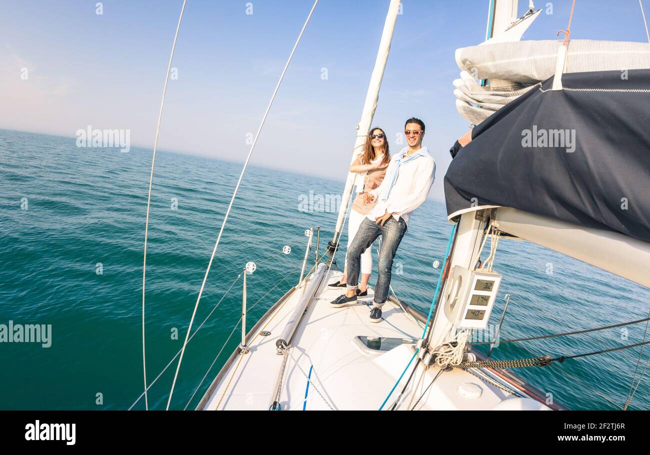 Young couple in love on sail boat having fun with champagne flute glasses - Happy exclusive travel concept on sailboat tour Stock Photo