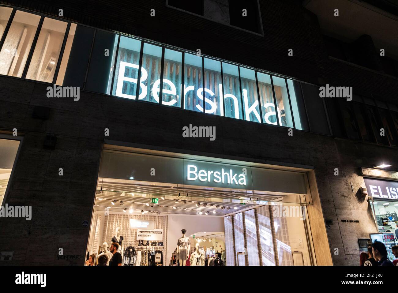 Naples, Italy - September 9, 2019: Facade of a Bershka clothing store at night with people around in Via Toledo, shopping street in Naples, Italy Stock Photo