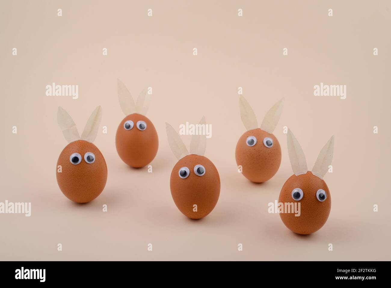 Easter Eggs with eyes and Rabbit ears on beige background. Copy space. Happy Easter concept. Stock Photo
