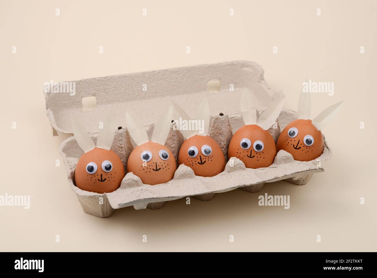 Easter eggs with eyes and rabbit ears in an egg container. Happy Easter concept. Stock Photo