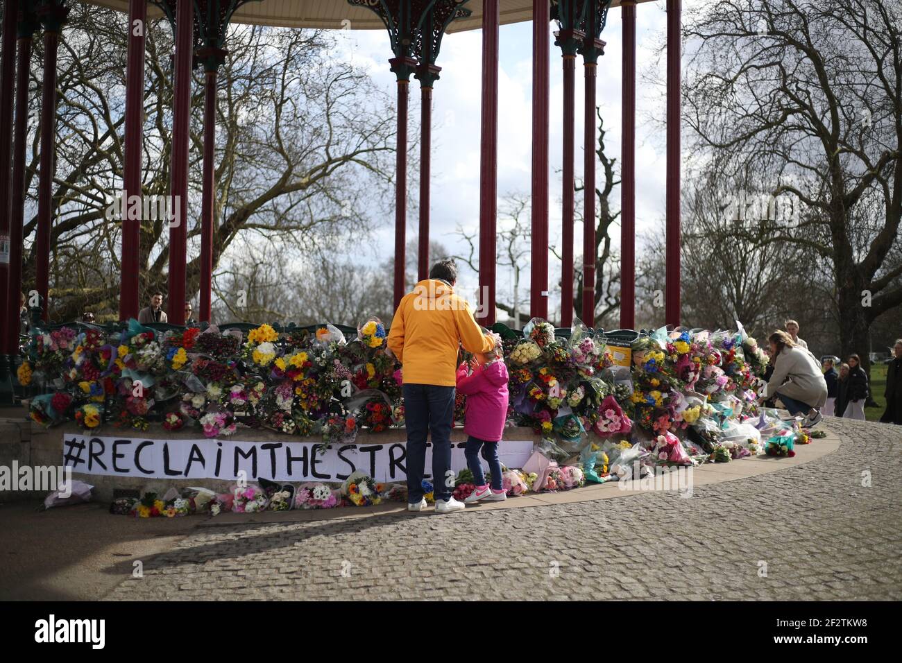 People place floral tributes for Sarah Everard at the band stand in Clapham Common, London, after the Reclaim These Streets vigil this evening was officially cancelled. Serving police constable Wayne Couzens, 48, was charged on Friday evening with kidnapping and killing the marketing executive, who went missing while walking home from a friend's flat in south London on March 3. Picture date: Saturday March 13, 2021. Stock Photo
