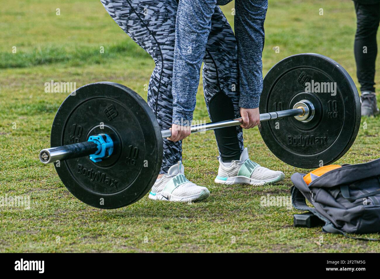 WIMBLEDON LONDON, UK 13 March 2021.  Cara exercises outdoors using weights is watched by her trainer Matthew on Wimbledon Common during lockdown on a cold blustery day. The government has started to relax lockdown restricitons allow people to meet and exercise outdoors as part of the roadmap to get back to normal life Credit amer ghazzal/Alamy Live News Stock Photo