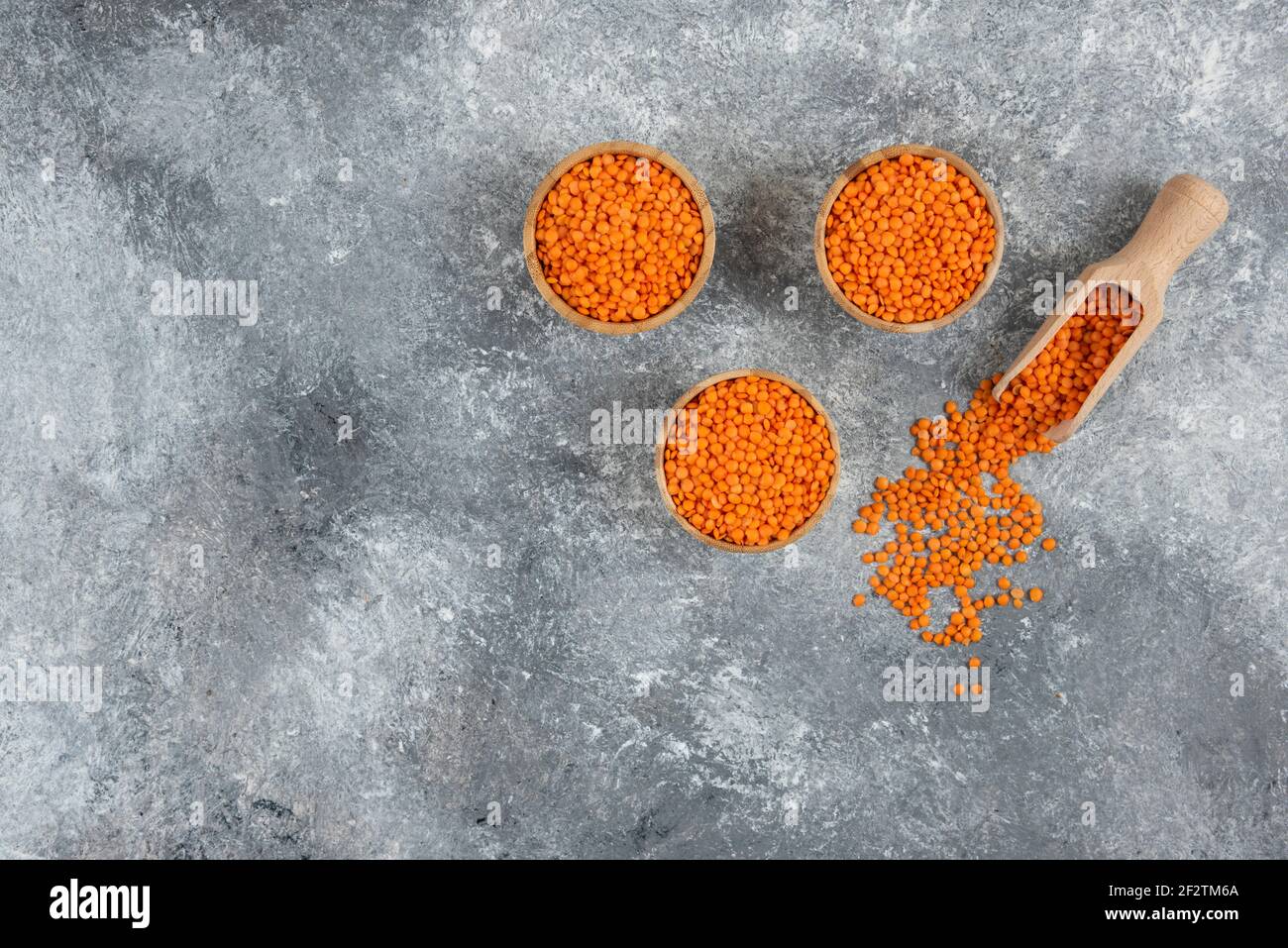 Wooden bowls of red raw lentils on marble background Stock Photo