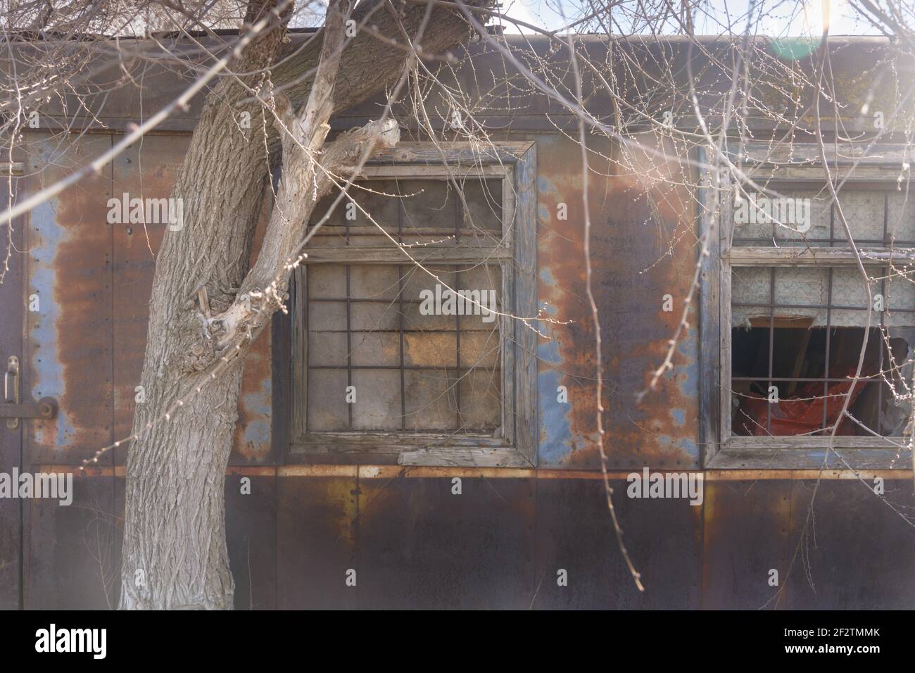Old abandoned iron building,  residential trailer with bars on windows. Rust and peeling paint on walls of facade. Stock Photo
