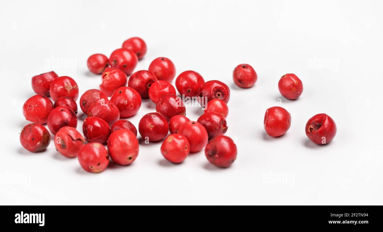 Red or Pink peppercorn scattered on board, closeup photo isolated with
