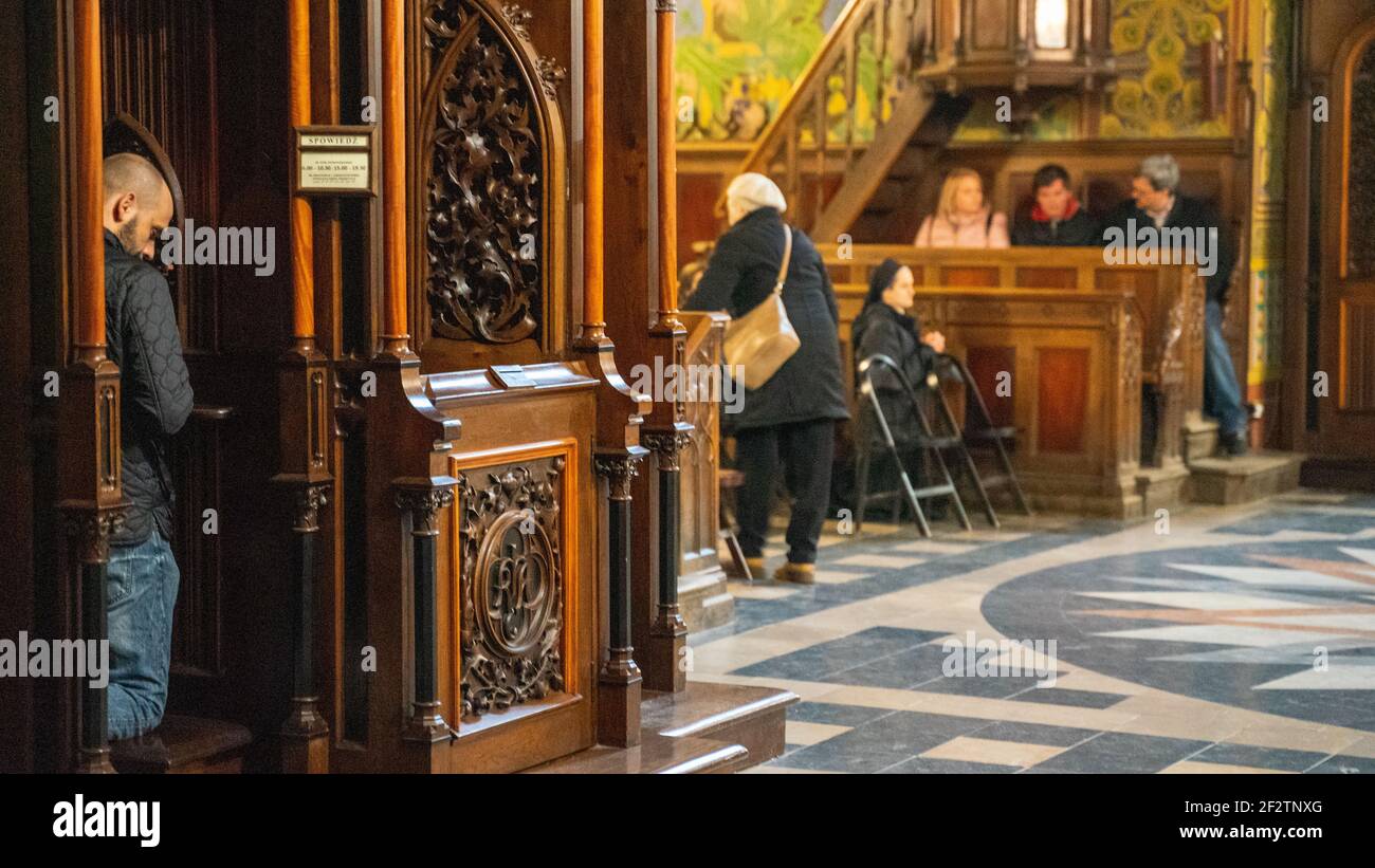The man, churchgoer or parishioner, penitent in the confession booth in the Catholic cathedral; with churchgoers Stock Photo