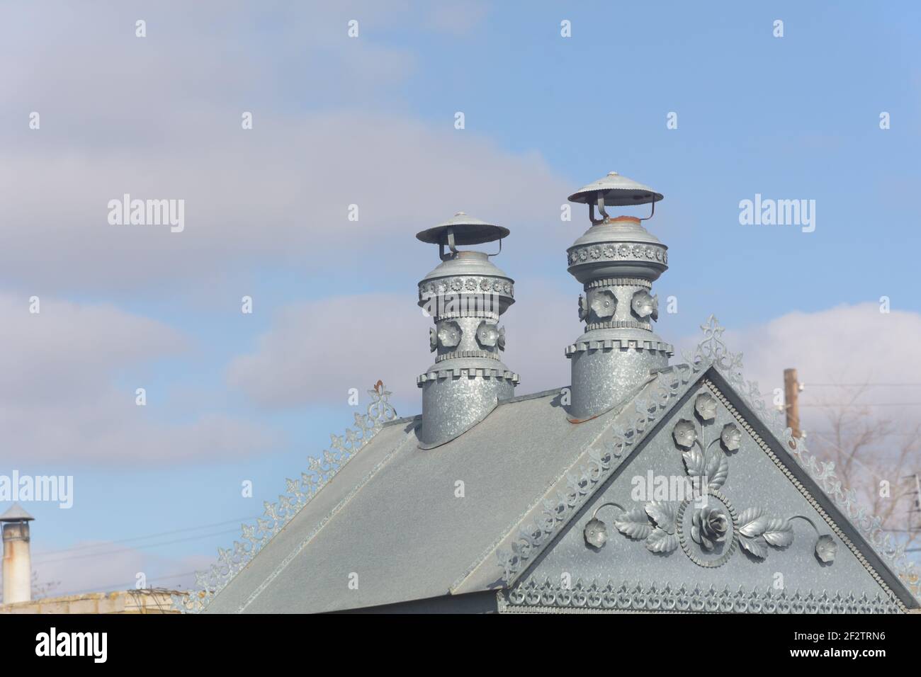 Small metal roof with iron patterns and pipes. Blue sky background. Stock Photo