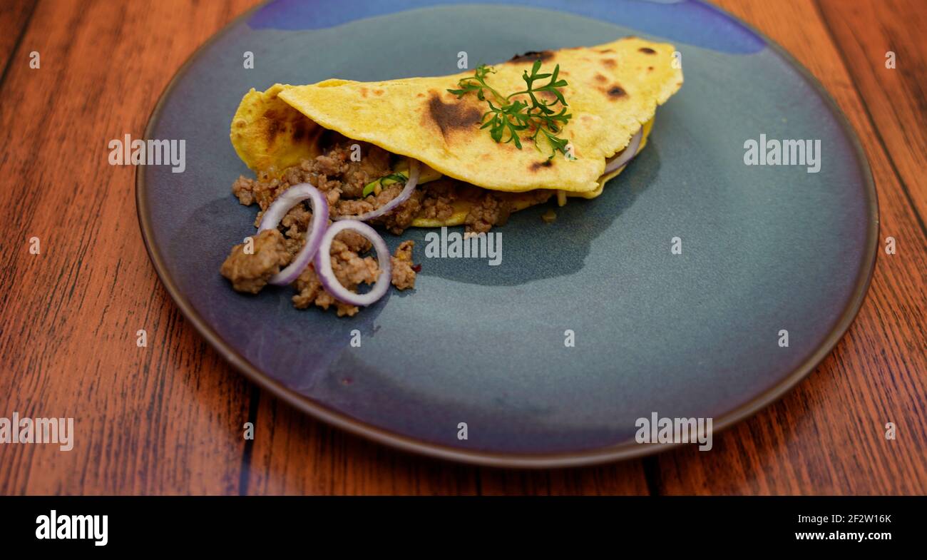 Taco with minced meat avocado onion filling arranged on a plate. Stock Photo