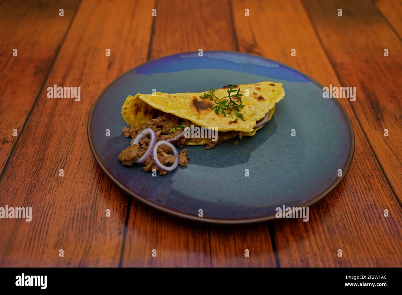 Taco with minced meat avocado onion filling arranged on a plate. Stock Photo
