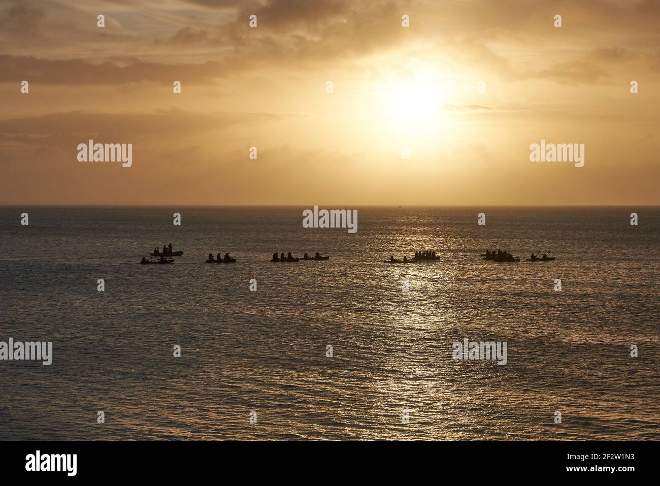 Sunrise by the sea with paddlers in rubber dinghies Stock Photo